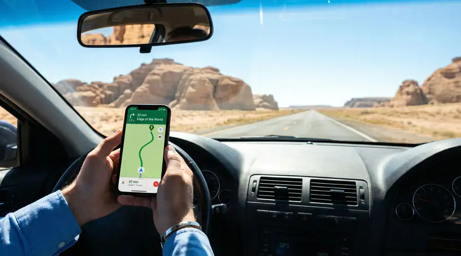 A dark SUV performing a sharp turn on a steep sand dune, kicking up a large cloud of sand.